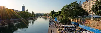 Menschen auf Liegenstühlen in der Sonne am Donaukanal