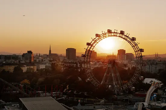 Ferris wheel in the Vienna Prater, Vienna skyline at sunset in the background