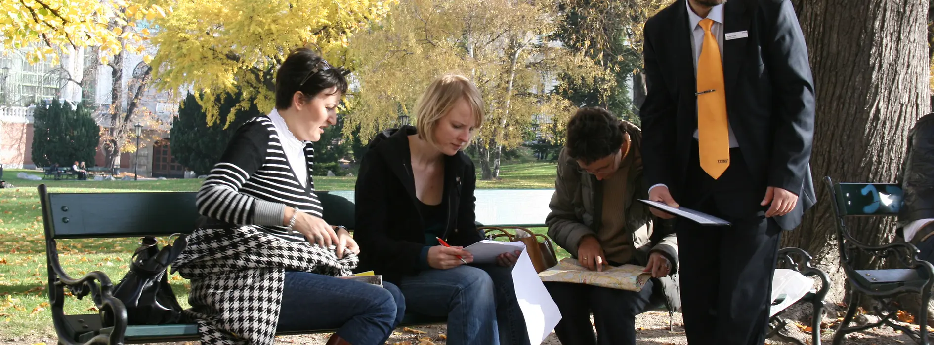 A group of people sitting in the park and solving a puzzle