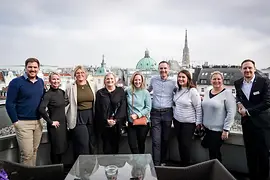 Group photo on balcony with Vienna backdrop