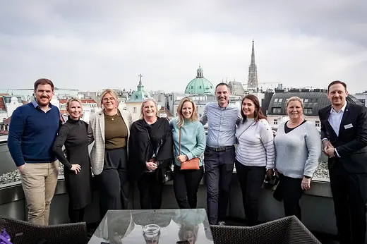 Group photo on balcony with Vienna backdrop