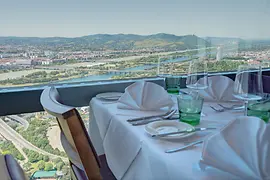 Donauturm Restaurant table set in front of a glass window with a panorama of Vienna in the background