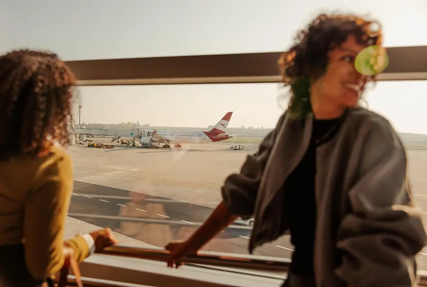 Zwei Frauen am Flughafen Wien, die aus dem Fenster auf das Rollfeld blicken